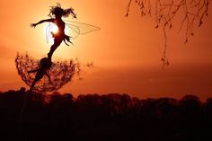 a silhouette of a woman on top of a dandelion with the sun in the background