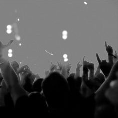 many people with their hands up in the air at a concert, some are throwing confetti into the air