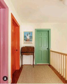 an entryway with two doors and a table in the middle, along with a painting on the wall