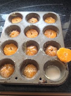 muffin tins filled with orange slices on top of a stove