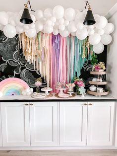 a rainbow themed party with balloons, streamers and tassels hanging from the ceiling