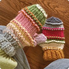 two knitted mittens sitting on top of a wooden floor next to each other