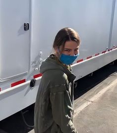 a woman wearing a blue face mask standing in front of a white trailer with the door open