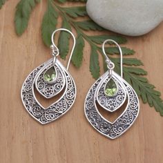 Two layers of sterling silver teardrop frames with an oxidized finish and intricate swirl motifs are crowned by shimmering peridot gemstones in this splendid design by Anya. The fashionable dangle earrings are an example of the traditional Balinese silversmith jewelry mastery, renowned around the world. Silversmith Jewelry, Silversmith Jewellery, Party Queen, Peridot Earrings, Gift Suggestions, Peridot Stone, Peridot Gemstone, Balinese, Jewelry Packaging