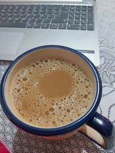 a cup of coffee sitting in front of a laptop