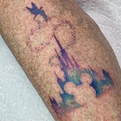 a man with a tattoo on his arm that has a castle and mickey mouse in it