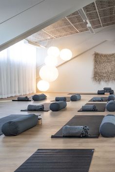 there are many yoga mats on the floor in this room with lights hanging from the ceiling