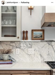 a kitchen with white marble counter tops and wooden cabinetry, along with a cross on the wall