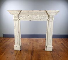 an antique white fireplace surround in a room with hard wood flooring and blue walls