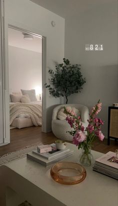 a living room filled with furniture and flowers on top of a coffee table in front of a bed