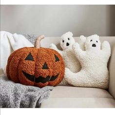 two pumpkins sitting on top of a couch with ghost pillows in front of them