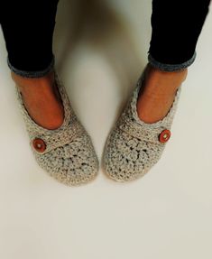 a woman's feet wearing crocheted slippers and black pants with buttons