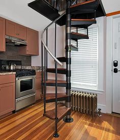 a spiral staircase in the middle of a kitchen with stainless steel appliances and wood flooring