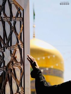 a person reaching for something on the side of a building with a yellow dome in the background