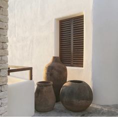 three vases sitting on the ground next to a window with shutters in it