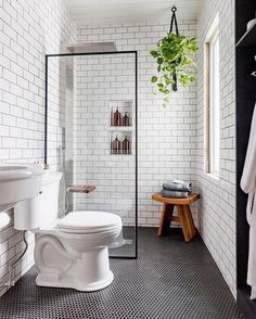 a white toilet sitting next to a shower in a bathroom with black and white tiles