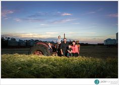 a group of people standing next to each other in front of a large tractor on a field