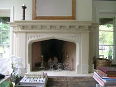 a living room with a fire place and books on the table in front of it