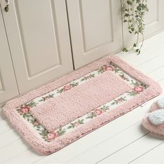 a pair of slippers sitting on the floor next to a pink mat with flowers