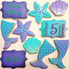 decorated cookies are arranged in the shape of mermaid tailes and seashells with happy birthday written on them