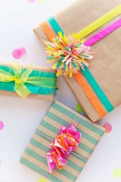 three wrapped presents with colorful ribbons and paper pom - poms on the top