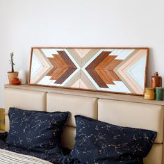 a bed topped with pillows next to a painting on top of a wooden headboard