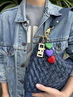 a woman is holding a purse with hearts on the front and an embellished keychain