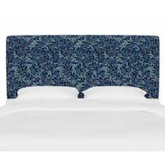 an upholstered headboard with white pillows and blue leaves on the back wall