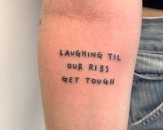 a person with a tattoo saying laughing til our ribs get tough on their left arm