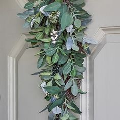 a wreath hanging from the side of a door with green leaves and berries on it