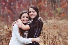 two young women hugging each other in a field