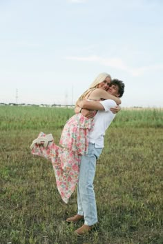 a man and woman hug in the middle of a field