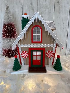 a gingerbread house decorated with candy canes and christmas decorations on top of snow