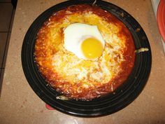 an egg is on top of some food in a black plate with red and orange plates