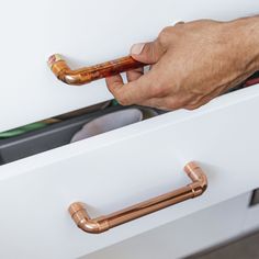 a person is holding a pipe in front of a drawer with other items on it