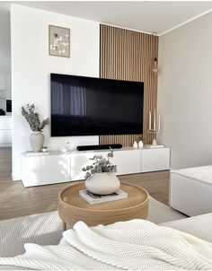 a living room with a large flat screen tv mounted on the wall above a wooden coffee table