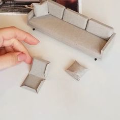 a person is pointing at some cardboard pieces on the table next to a couch and coffee table