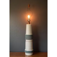 a lamp that is sitting on top of a wooden table in front of a gray wall