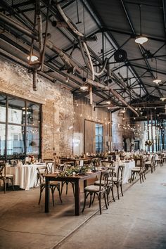 an empty room with tables and chairs set up for a wedding reception in front of large windows