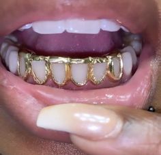 a close up of a person's mouth with gold teeth