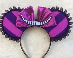 a purple and black minnie mouse ears headband with a smile on it's face