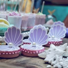 there are some little mermaid themed treats on the table with pink and purple decorations around them