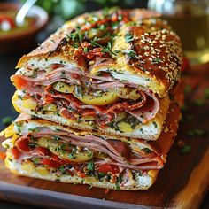 two sandwiches stacked on top of each other with meat, cheese and tomato toppings