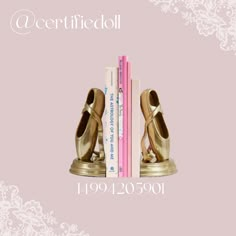 a pair of gold shoes sitting on top of a bookshelf next to a pink book