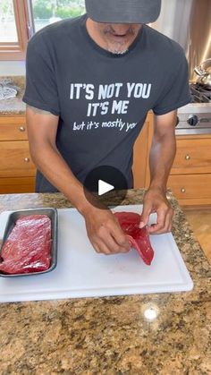 a man cutting up meat on top of a counter