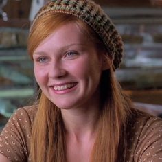 a woman with long red hair wearing a knitted hat and smiling at the camera