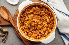 a casserole dish with meat and vegetables in it on a wooden cutting board