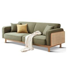 a green couch with pillows on it and a white blanket draped over the armrests