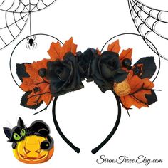 a mickey mouse ears headband with black flowers and leaves on it, next to a pumpkin