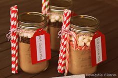 four mason jars with candy canes in them on a wooden table next to two red and white striped paper straws